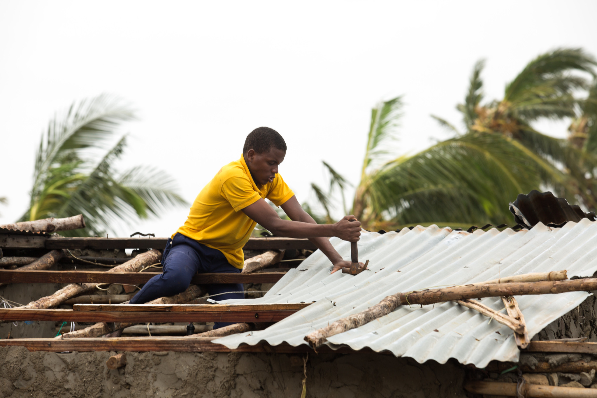 IDAI Aftermath - A man fixes the roof of his house in Praia Nova