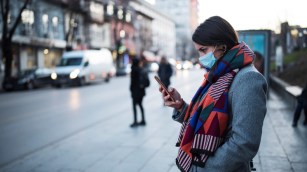 young woman with face mask using smartphone-GND-iStock